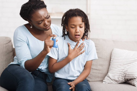 黑人母亲为女儿拿着哮喘吸入器