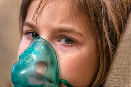 可爱的小女孩通过雾化吸入器呼吸.健康照片