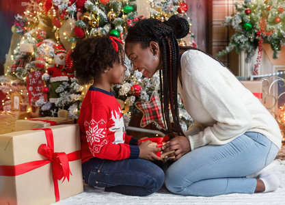 慈爱的黑人母亲给她的小女儿送圣诞礼物