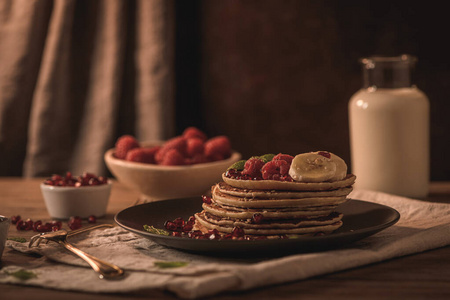 Pancakes with raspberries, banana slices, pomegranate seeds and 