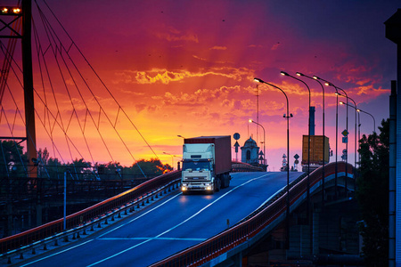 卡车载着集装箱在桥上驰骋，美丽的夕阳，货车在工业海港，公路就往上走