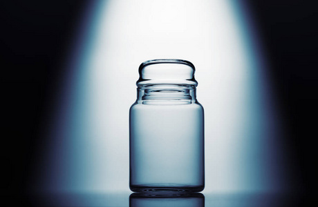 Empty glass jar on a blue and white background with light effect