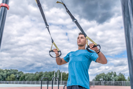 运动型男子运动带环trx,拉起和训练胸肌,在城市的夏季锻炼,积极的生活