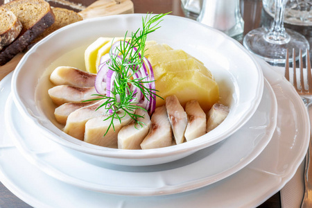 Salted herring and boiled potato cut on the slices in the white 