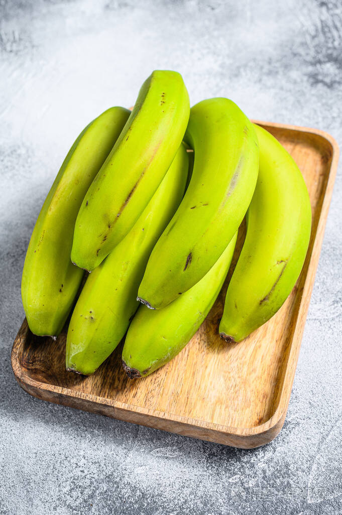 木制托盘上的绿色香蕉灰色背景俯视图热带水果