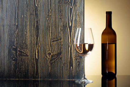 Bottle and glass of white wine on a black table. 