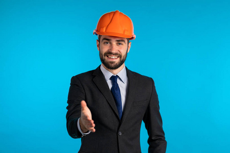 Young engineer businessman in construction helmet holds out his 