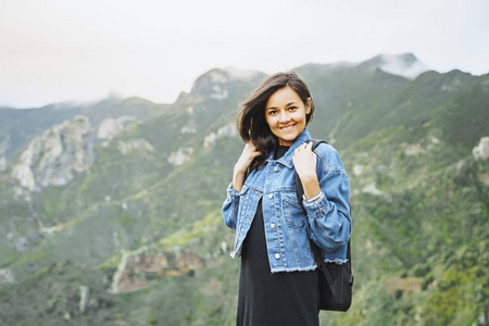 快乐微笑的女人背着背包在山上。旅游和生活方式概念