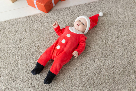 美丽的小宝宝庆祝圣诞节。新年假期。婴儿穿着圣诞服装，戴着圣诞帽，俯视图