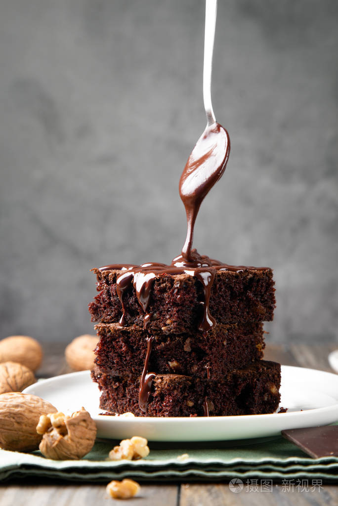 用勺子把融化的巧克力倒在布朗尼上