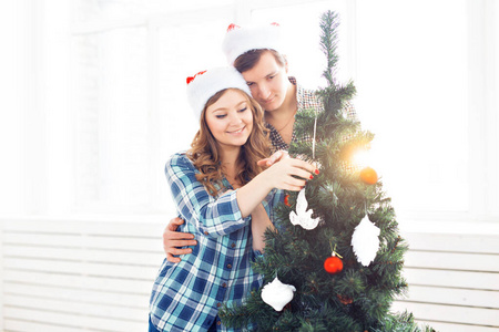 家庭，圣诞，寒假和人的概念快乐的年轻夫妇装饰圣诞树在家