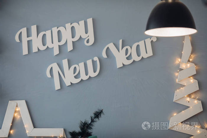 美丽的白字在现代装饰工作室的蓝墙新年快乐