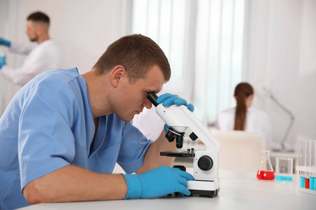 在桌上用显微镜的科学家和实验室里的同事