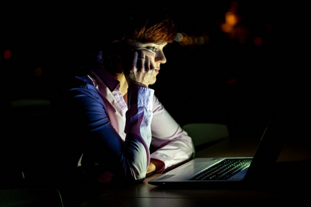 一个年轻漂亮的女人在大学演讲，晚上在笔记本电脑上工作