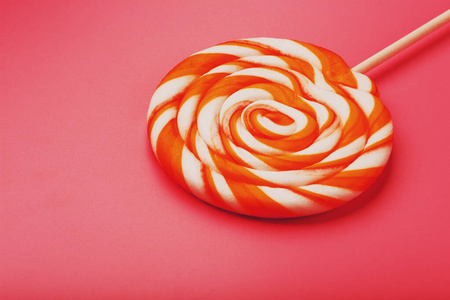 橙色棒棒糖在粉红色的背景与柔和的对比.最小的概念和复制空间.照片
