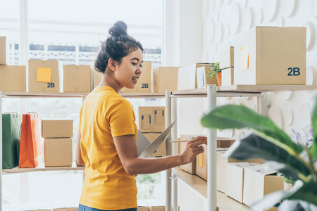  young Asian woman  checking goods on stock shelf at warehouse