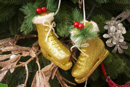 圣诞树树枝上的圣诞玩具金溜冰鞋。装饰圣诞树特写