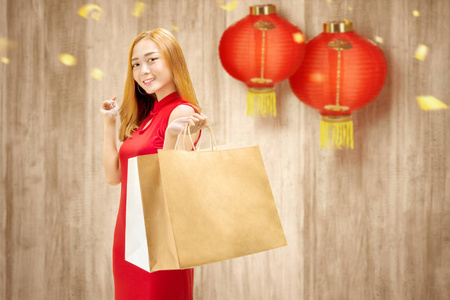 Asian Chinese woman in cheongsam dress holding shopping bags 