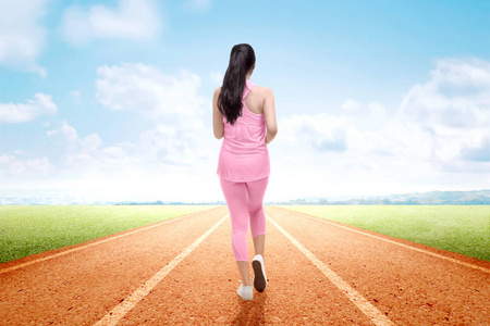 亚洲女跑步者在跑道上奔跑的后视图运动员在跑道上奔跑, 有障碍跳跃