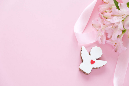 天使形状的饼干，粉红色的背景上有一条粉红色的蝴蝶花。