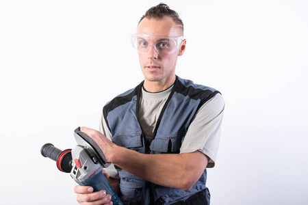 戴着护目镜的建筑工人,手里拿着角磨机.照片