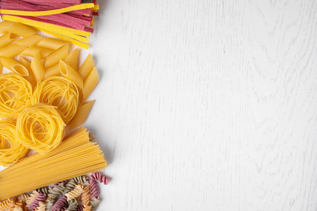 Different types of pasta on white wooden table, flat lay. Space 