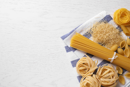 Different types of pasta on white wooden table, flat lay. Space 