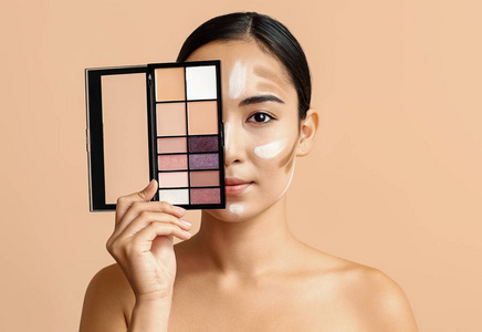 年轻的亚洲女性，用化妆品在彩色背景上画出轮廓