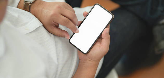 Cropped shot of man using his blank screen smartphone while sitt