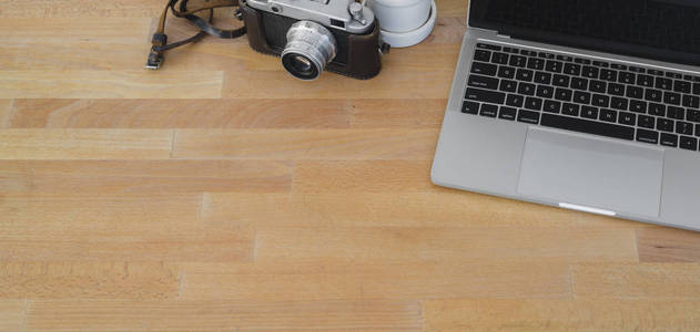 舒适工作场所的俯视图，带笔记本电脑和摄像头，背景为木制桌子