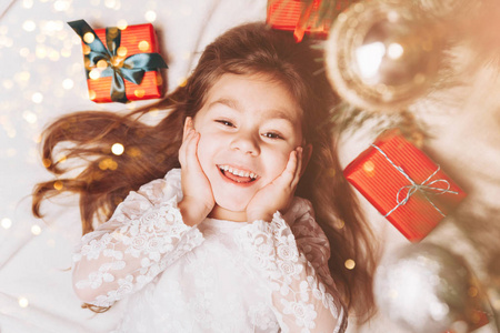 可爱快乐的小女孩在圣诞气氛中欢笑，礼物盒和魔法灯。