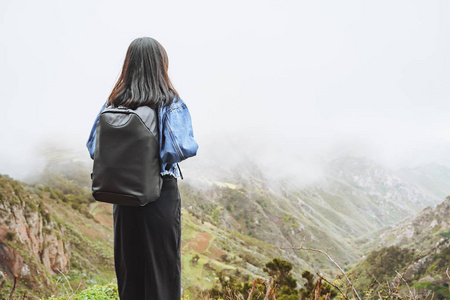 背着背包的年轻女游客在山顶上放松，欣赏山谷的景色