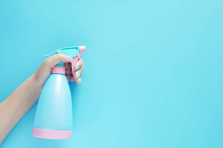 女士手持清洁喷雾蓝色塑料瓶清洁剂隔离在蓝色背景上，带有文本或徽标的复印空间