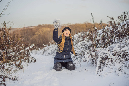 冬天的女孩向镜头扔雪球微笑着快乐地在下雪的冬日户外玩耍.