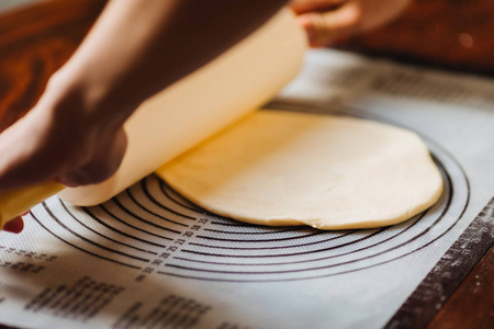 Female chef cook hands rolling dough with pin. 