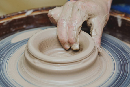 女人手放在陶轮上。工匠艺术家塑造壶