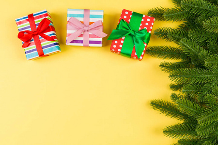 彩色背景下的礼品盒和冷杉树枝的俯视图。圣诞快乐概念，为您的设计留出空间