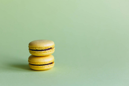 Two yellow french macarons on the light green background. Banana