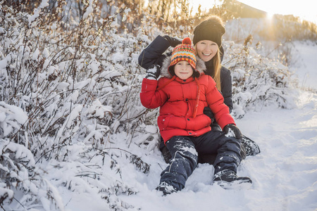 冬日雪天，冬日母子俩在雪地里嬉戏，笑嘻嘻地向镜头扔雪球。可爱俏皮的年轻女子在户外享受初雪