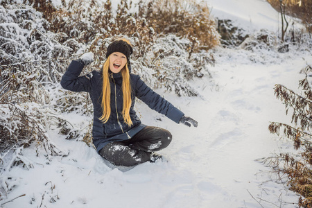 冬天的女孩向镜头扔雪球微笑着快乐地在下雪的冬日户外玩耍。可爱俏皮的年轻女子在户外享受初雪