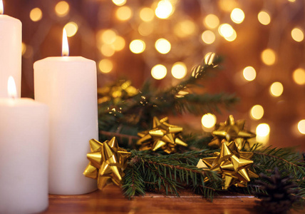 圣诞树枝上的金色圣诞球，棕色背景上点缀着星星的白色烛光