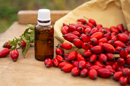 Rosehips and rose hip seed oil on the wooden table. Rose hip  c