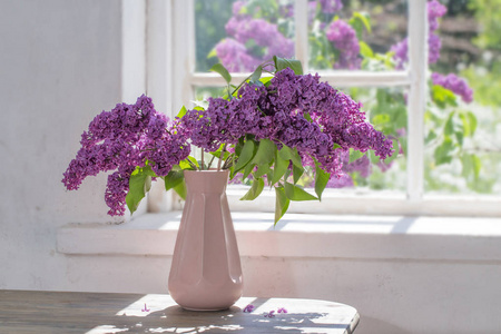 阳光明媚的日子里，花瓶里的丁香花靠着窗户