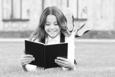 知识不仅仅是信息。快乐的小女孩在绿草上看书。可爱的小学生从阅读中获得知识。知识日或9月1日。测试你的学校知识