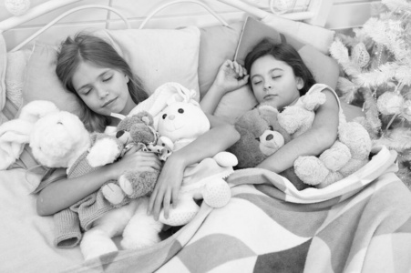 寒假休息.睡觉的孩子.小孩子们睡在圣诞树旁.小女孩抱着玩具躺在床上.