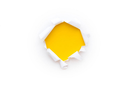 白纸上的一个圆孔，边缘被撕破，隔离在白色背景上，内有亮黄色的纸张背景。