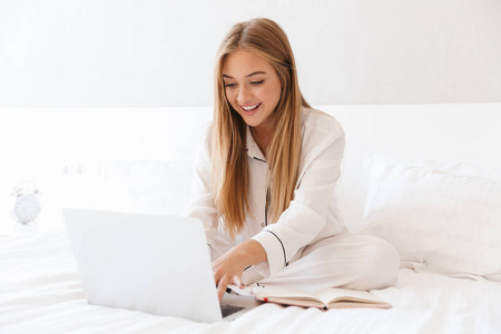 年轻快乐女人在笔记本电脑上打字微笑的照片