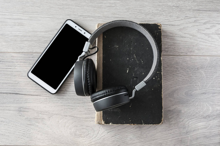 headphones, smartphone and open blank book on wooden table. Top 