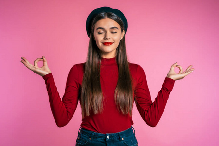 女人平静下来,深呼吸,在粉红色的背景下闭上眼睛.摄影棚镜头照片