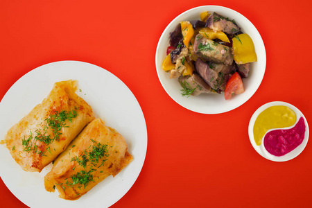  cabbage rolls in a white plate with vegetable salad and sauce. 